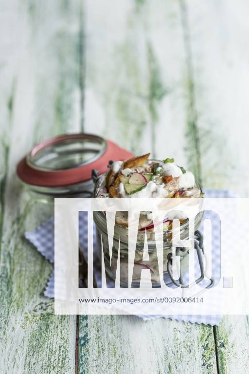 Glass of fried potato salad with cucumber, red radish, spring onions and mayonnaise yoghurt dressing STBF00314
