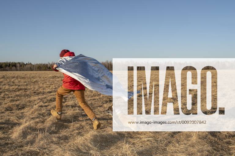 Boy dressed up as superhero running with dog in steppe landscape model released Symbolfoto property released VPIF01226
