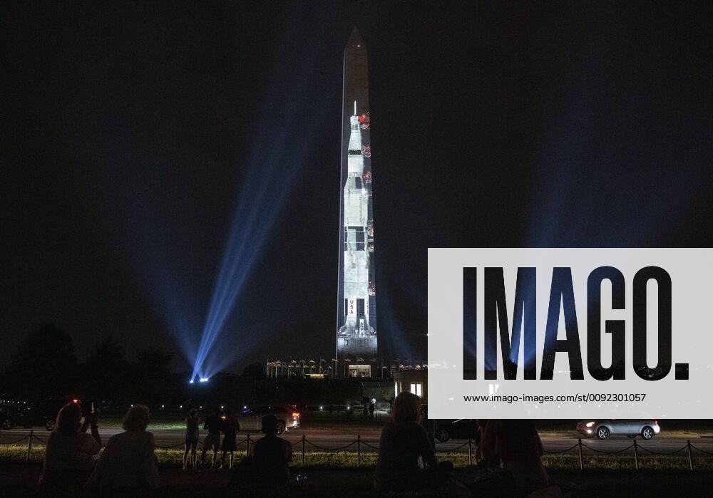 People watch as the Saturn V rocket that took Apollo 11 to the moon is displayed on the Washington Monument on the National Mall during a light show in Washington, DC on Tuesday, July 16, 2019. The Smithsonian and NASA are celebrating the 50 years of Apollo 11 that took man to the moon. Neil Armstrong, Buzz Aldrin and Michael Collins took off from Earth on July 16, 1969 and Armstrong and Aldrin landed on the moon on July 20, 1969. WAP20190712044 PATxBENIC