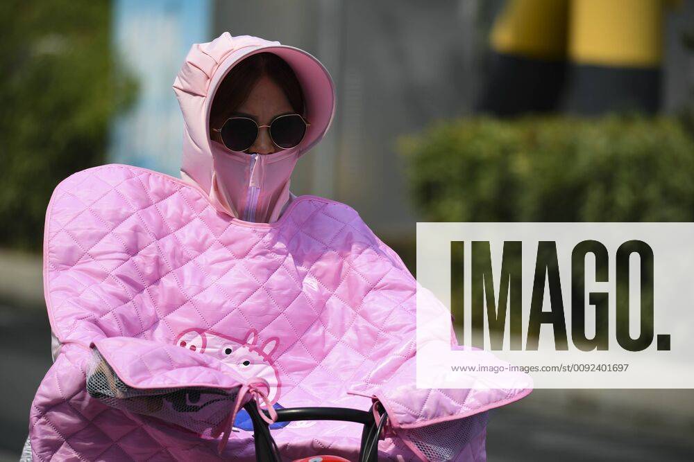 A citizen wearing a hat, a facemask and a blanket rides amid heat one day ahead of Major Heat on July 22, 2019 in Bozhou, Anhui Province of China. Major Heat, the 12th solar term of the year, will begin on July 23 this year. The recent temperature in Bozhou soared above 35 degrees Celsius.