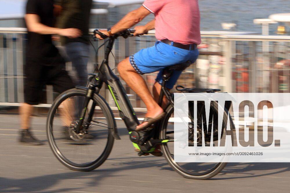 Man riding an electric bicycle on the riverside promenade on the Rhine in downtown Cologne, North Rhine-Westphalia, Germany