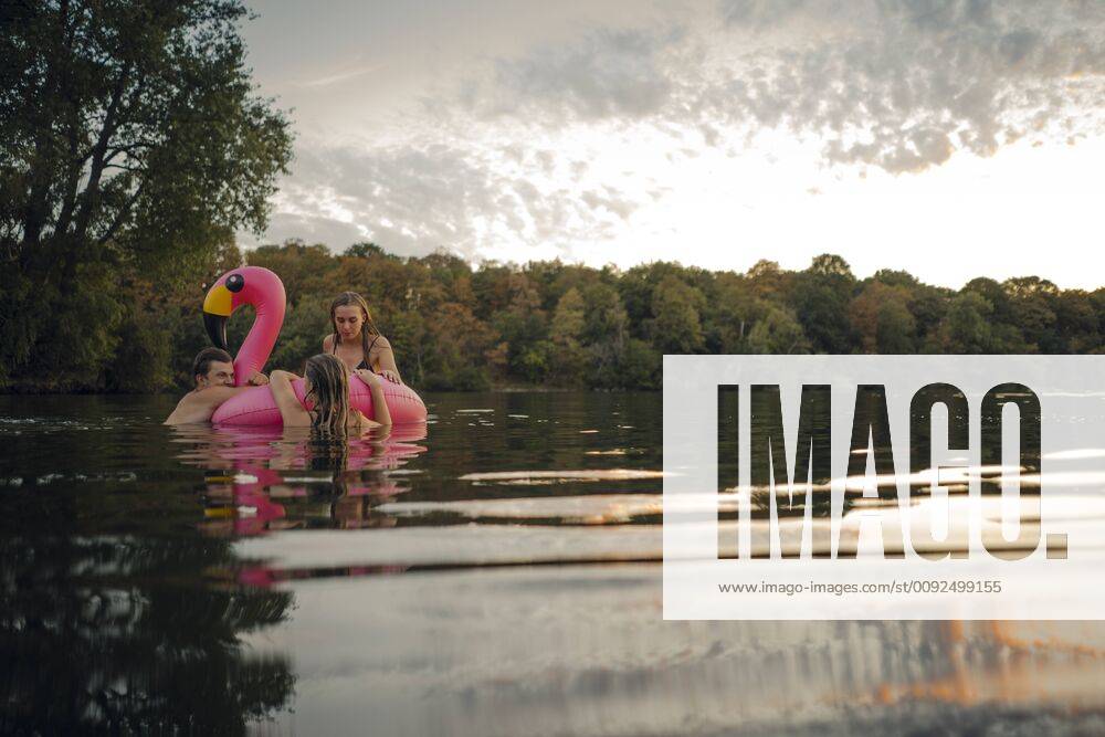 Friends having fun on a lake on a pink flamingo floating tire model released Symbolfoto GUSF02324