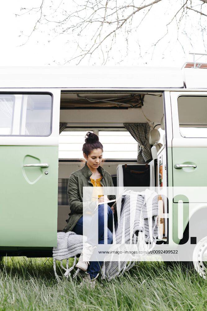 Young woman sitting in her camper, writing in a notebook model released Symbolfoto property released HMEF00437