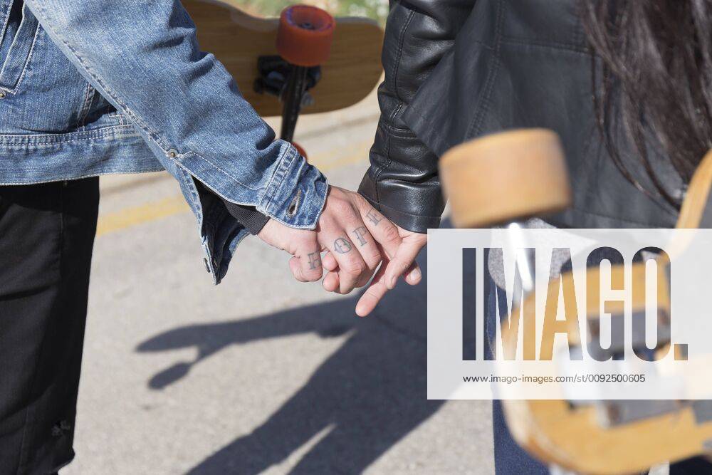 Tattooed young man holding hand with his girlfriend, partial view model released Symbolfoto JPTF00133