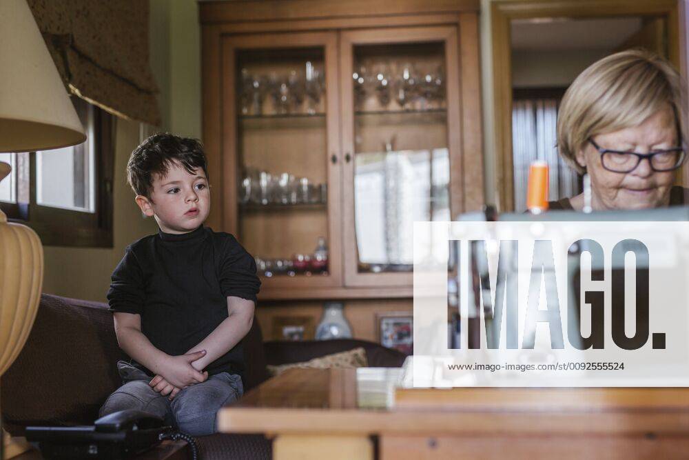 Grandmother using an old sewing machine watched by her grandson model released Symbolfoto property released LJF00090