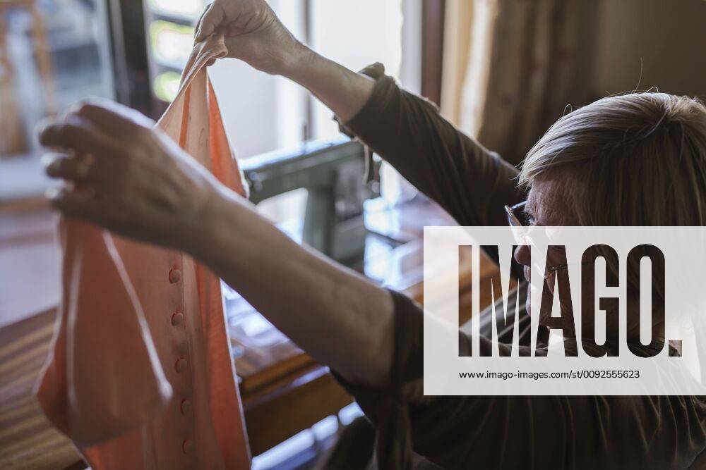 Senior woman holding a piece of clothing at home model released Symbolfoto property released LJF00116
