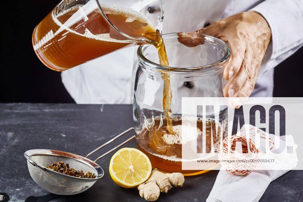 Man pouring kombucha SCOBY tea into jar