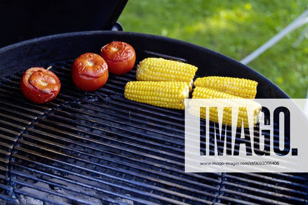 DEU, Germany, Münsingen, Baden Württemberg, 24 08 2019 Barbecue in the garden Tomatoes and maize lying on the grill