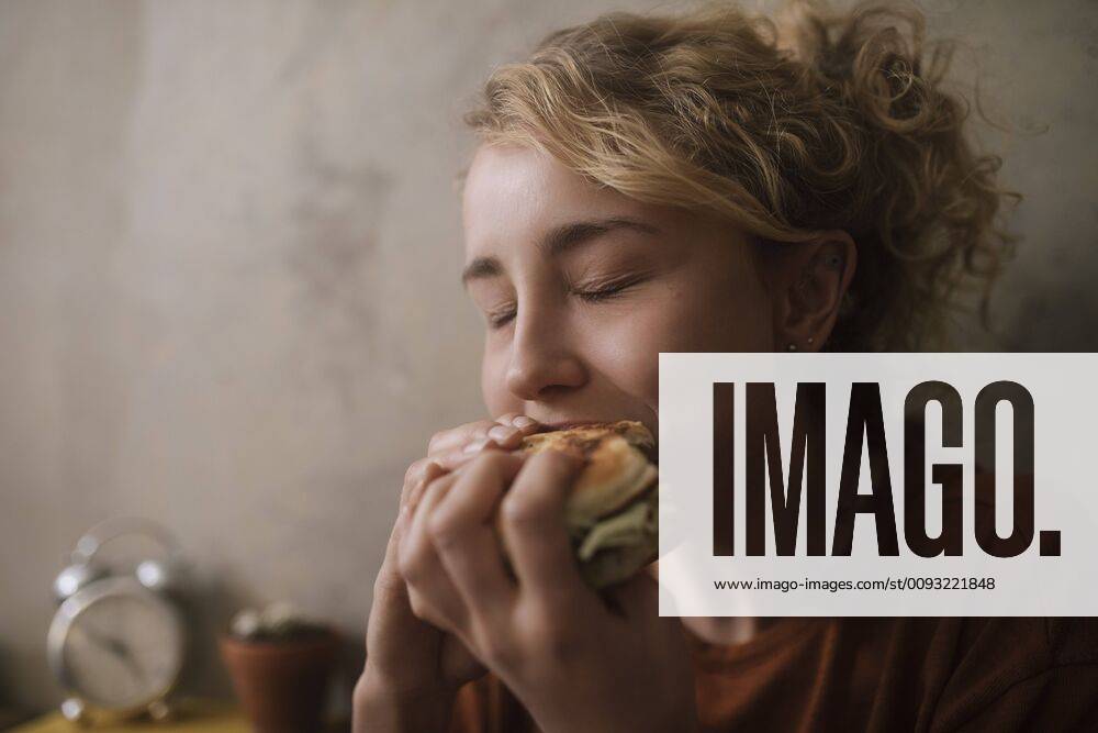 Portrait of young woman eating Hamburger model released Symbolfoto property released GCF00311
