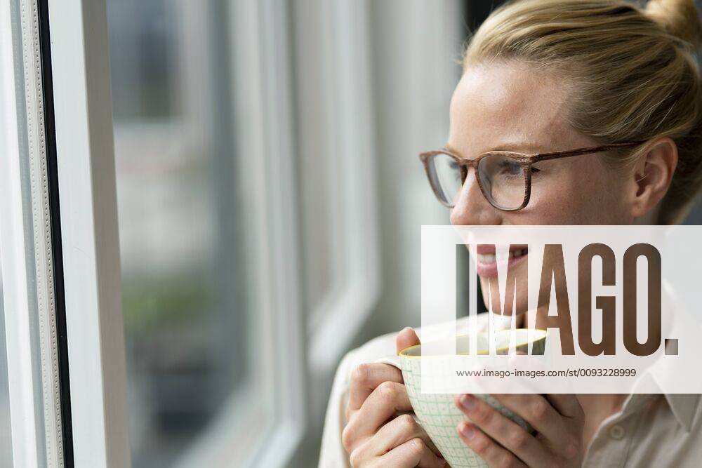 Young businesswoman with cup of coffee looking out of window model released Symbolfoto property released JOSF03531