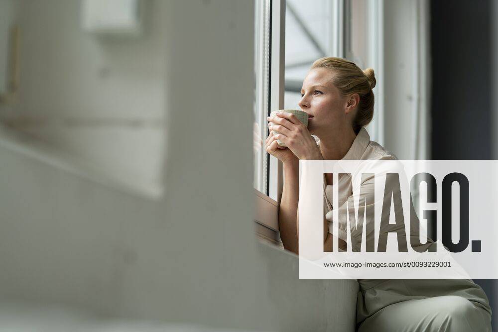 Young businesswoman with cup of coffee looking out of window model released Symbolfoto property released JOSF03532