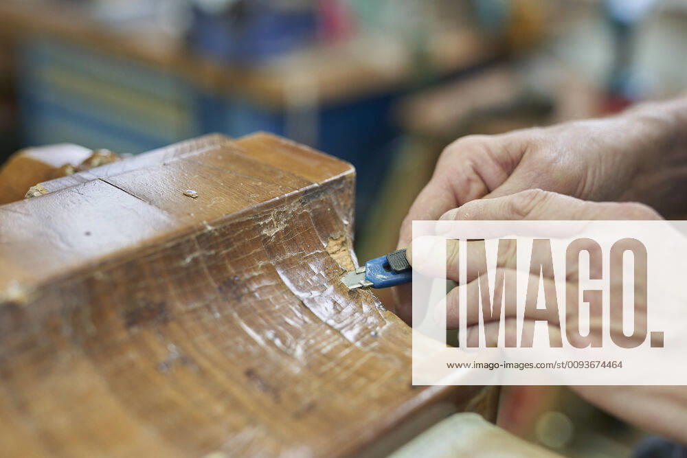 Hands of an antique carpenter removing a veneer from a cabinet foot Russikon, Switzerland 1082501450