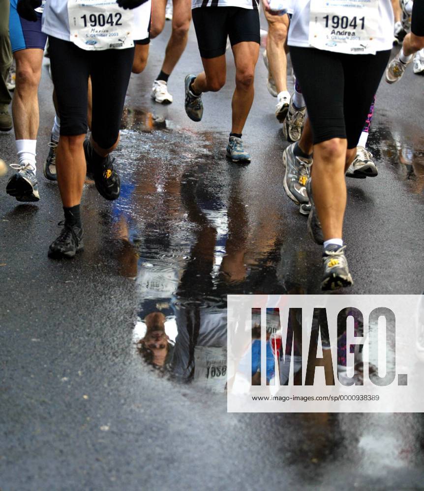 Marathonläufer spiegeln sich in den zahlreichen Pfützen, die sich auf der Straße gebildet haben Leichtathletik Köln-Marathon 2003, Stadtmarathon, Citymarathon, Marathonlauf, Langstrecke Gruppe Köln Dynamik,