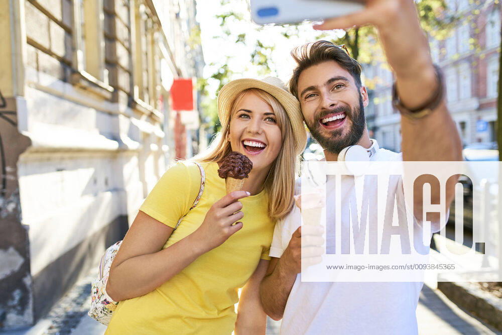 Happy young couple taking a selfie while eating ice cream in the city model released Symbolfoto BSZF01369