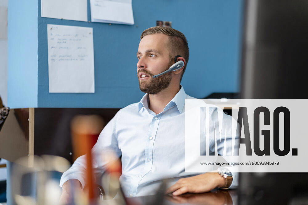 Businessman with headset at desk in office model released Symbolfoto property released DIGF07942