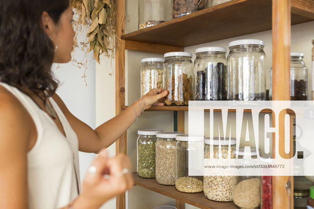 Young woman in organic shop looking at cereals in glass jars model released Symbolfoto property released JPTF00287