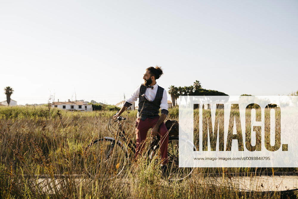 Well dressed man with his bike on a wooden walkway in the countryside having a break model released Symbolfoto JRFF03583