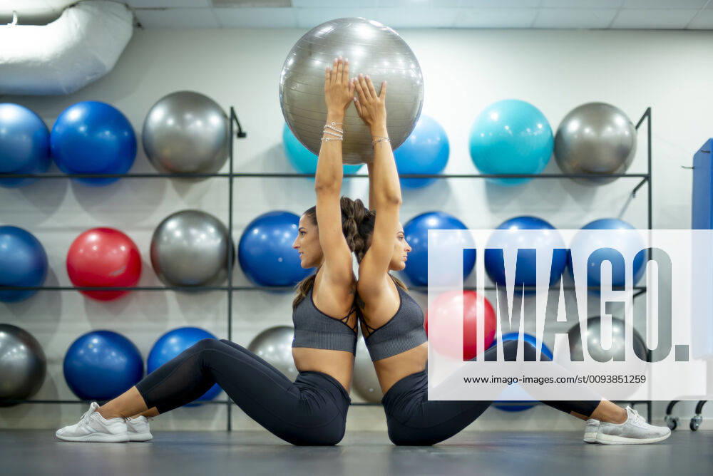 Twin sisters in gym practicing with a fitness ball model released Symbolfoto property released OCMF00657