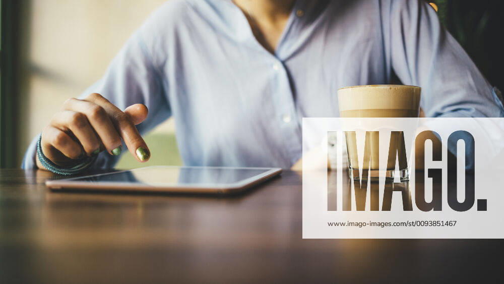Woman sitting in a cafe using a digital tablet and drinking a coffee model released Symbolfoto OYF00053