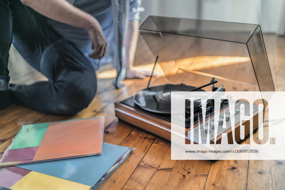 Close-up of man sitting on the floor at home with a record player model released Symbolfoto property released RIBF01028