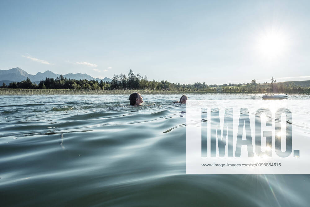 Two girls swimming in a lake in sunshine, Bannwaldsee, Allgaeu, Bavaria, Germany model released Symbolfoto WFF00088