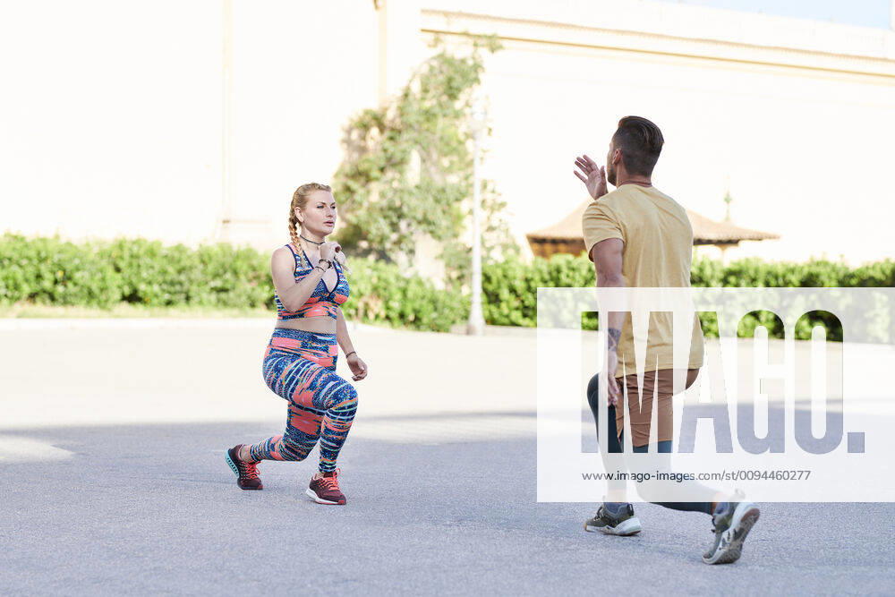 Fitness coach practicing with young woman outdoors in the city model released Symbolfoto JNDF00089