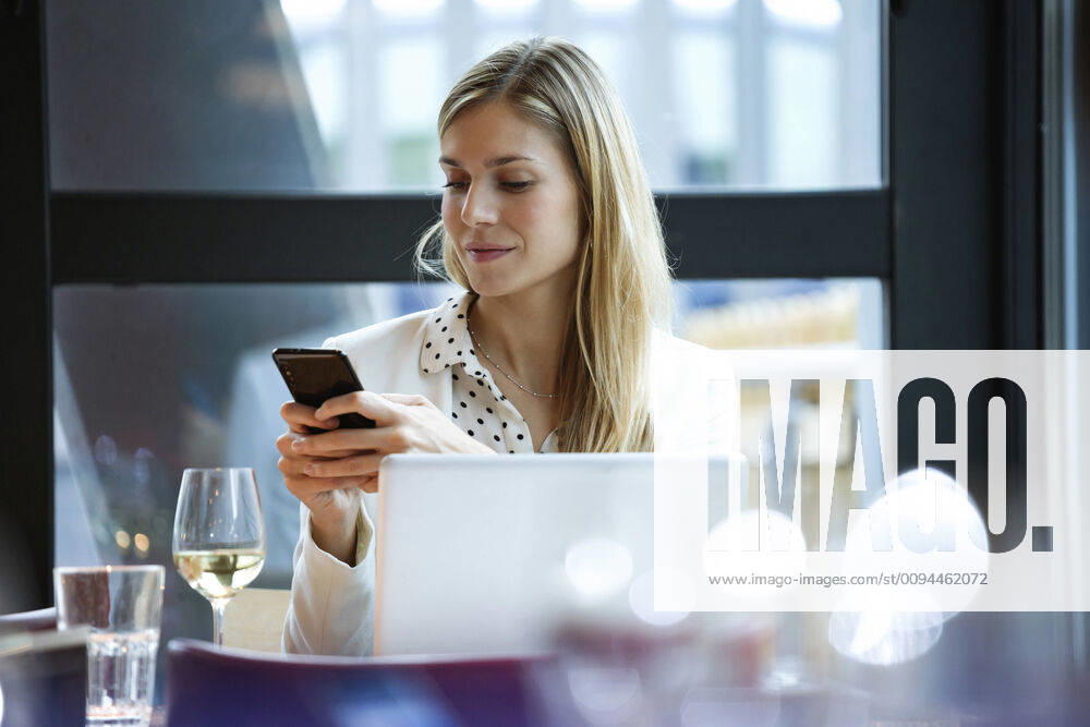 Businesswoman using cell phone in a restaurant model released Symbolfoto property released JSRF00618