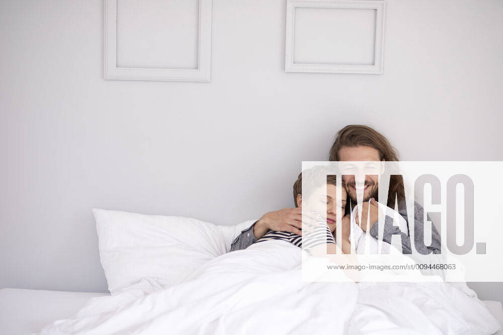 Happy young couple cuddling in bed at home model released Symbolfoto property released MJFKF00073
