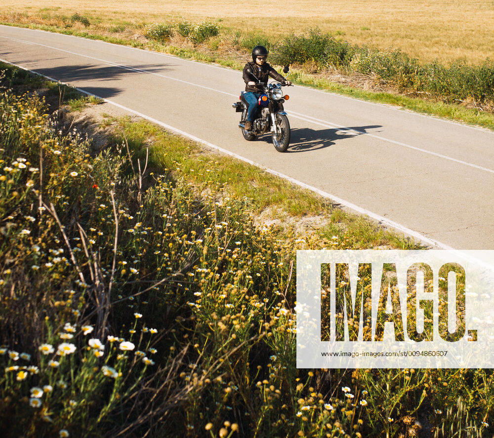 Young man riding his black motorcycle on the road with his helmet on Spain, Andalusia, Seville CR_FAGU191022-207988-01