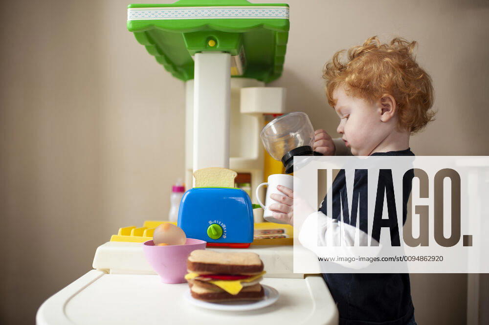 Toddler boy playing in toy kitchen pretending to pour coffee into cup United States, Iowa, Grimes CR_LIPF191001-197516-01