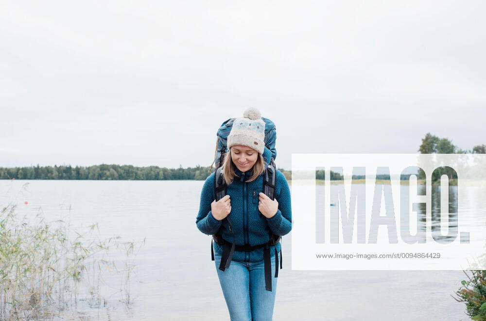 Woman smiling backpacking by the beach Sweden, Stockholm County, Norrtälje CR_RABE191022-210187-01