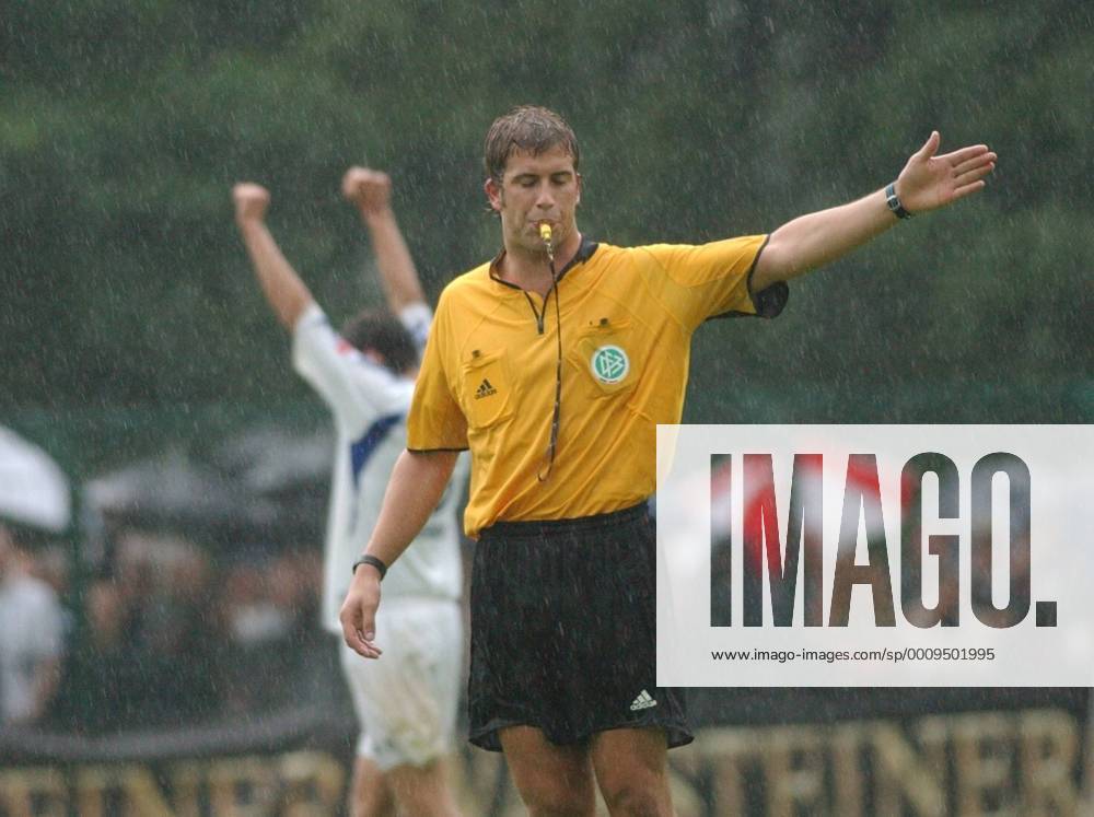 Robert Hoyzer (Schiedsrichter) 08 04 hör Mann Fußball Profifußball Bundesliga Pokal Pokalspiel DFB Schiedsrichter Unparteiischer kurzhaarig dunkelhaarig sportlich Trikot leger quer halb stehend draußen Spielfeld Partie Spiel Gestik gestikulierend Augen zu geschlossen pfeifend Pfeife Regen nass Nässe durchnässt Logo Pokalspiel SC Paderborn 07 gegen Hamburger SV (HSV) am 21.08.2004 in Paderborn (Ergebnis 4:2)