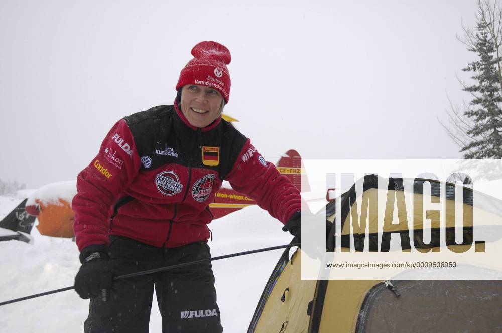Jutta Kleinschmidt bei der Fulda Challenge 2005 in Kanada 02 05 mapo Frau Sportlerin Motorsport Motorsportlerin Autosport Auto Rallye Rallyesport Rallyefahrerin sportlich Sportkleidung Mütze halb quer stehend draußen lächelnd zur Seite schauend am Zelt