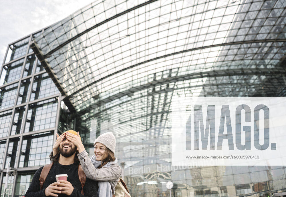 Happy young woman surprising boyfriend at the central station, Berlin, Germany model released Symbolfoto AHSF01483