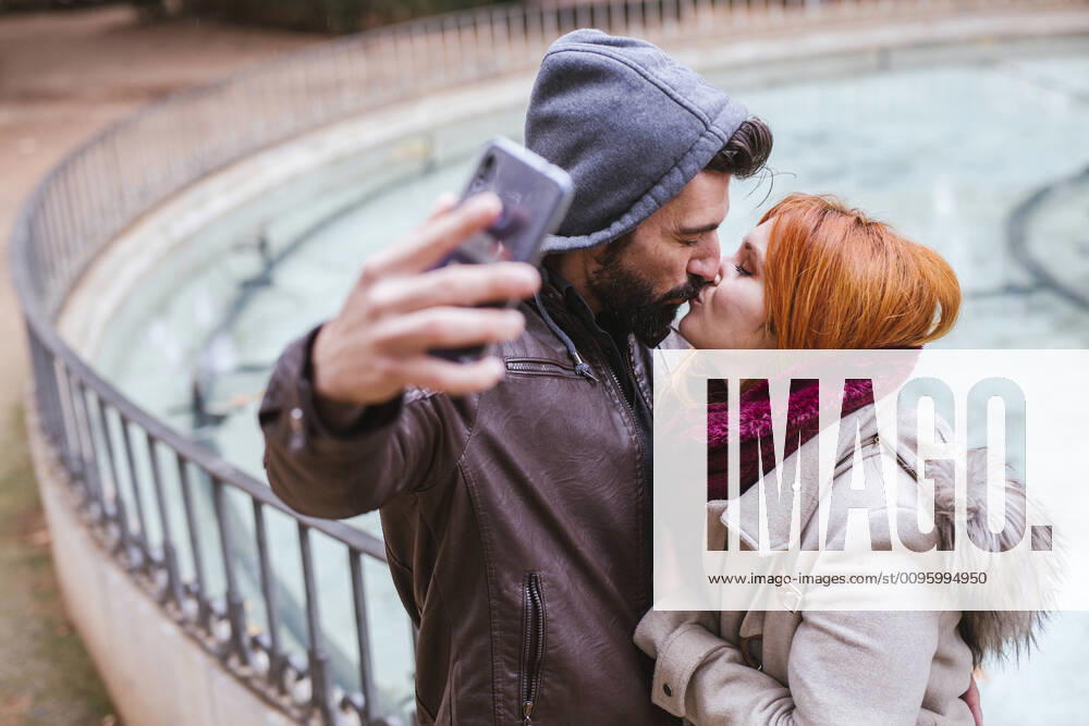 Kissing couple taking selfie with smartphone model released Symbolfoto LJF01157