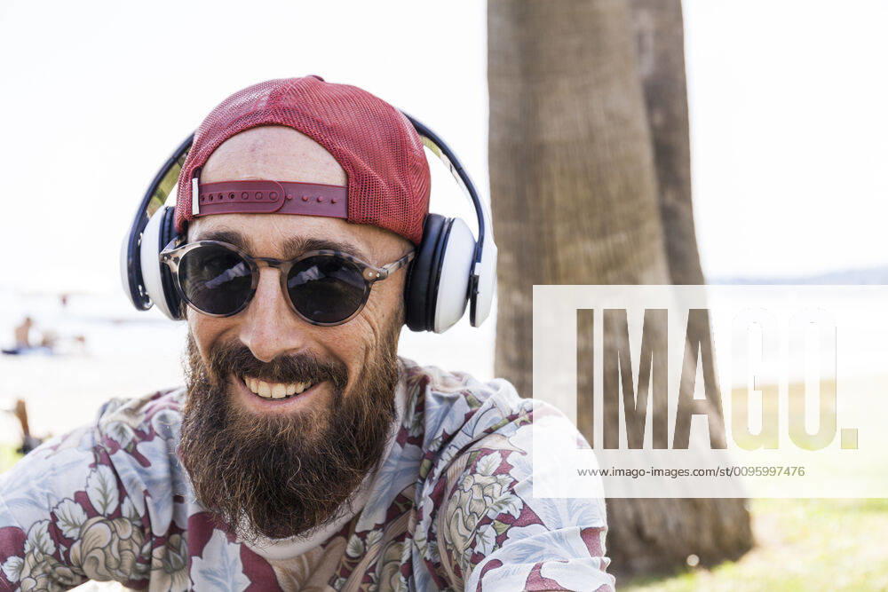 Mature man with red basecap, sunglasses and white headphones model released Symbolfoto TCF06231