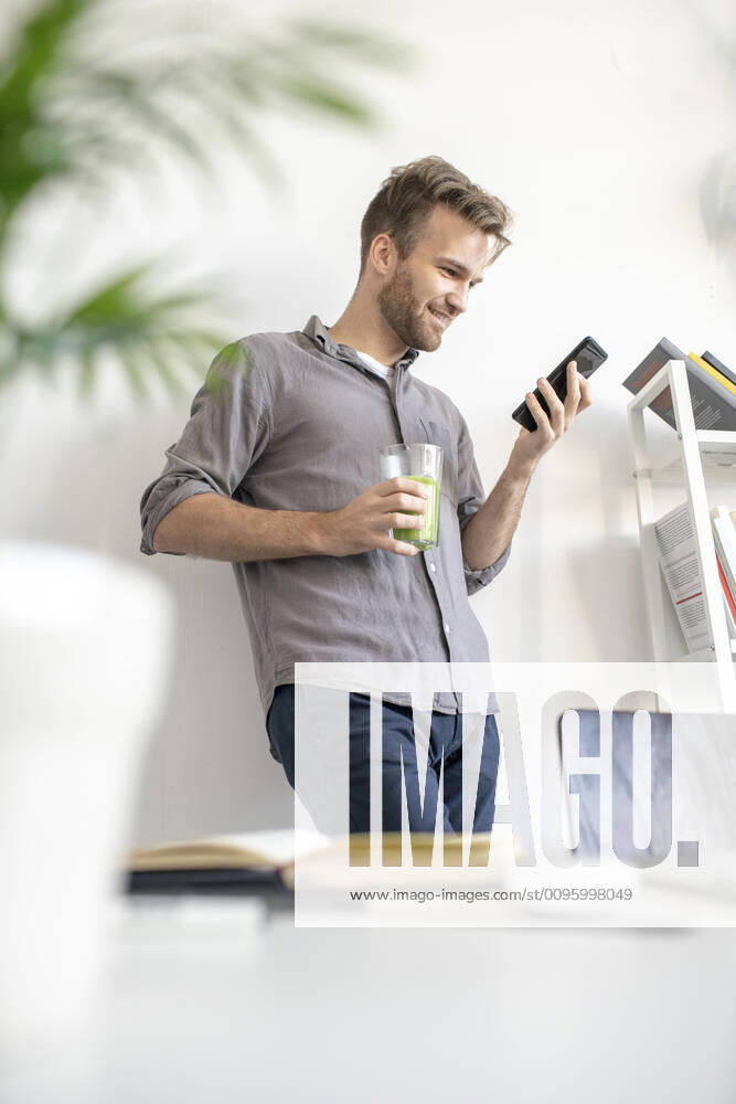 Smiling man using smartphone in office model released Symbolfoto property released VPIF01788