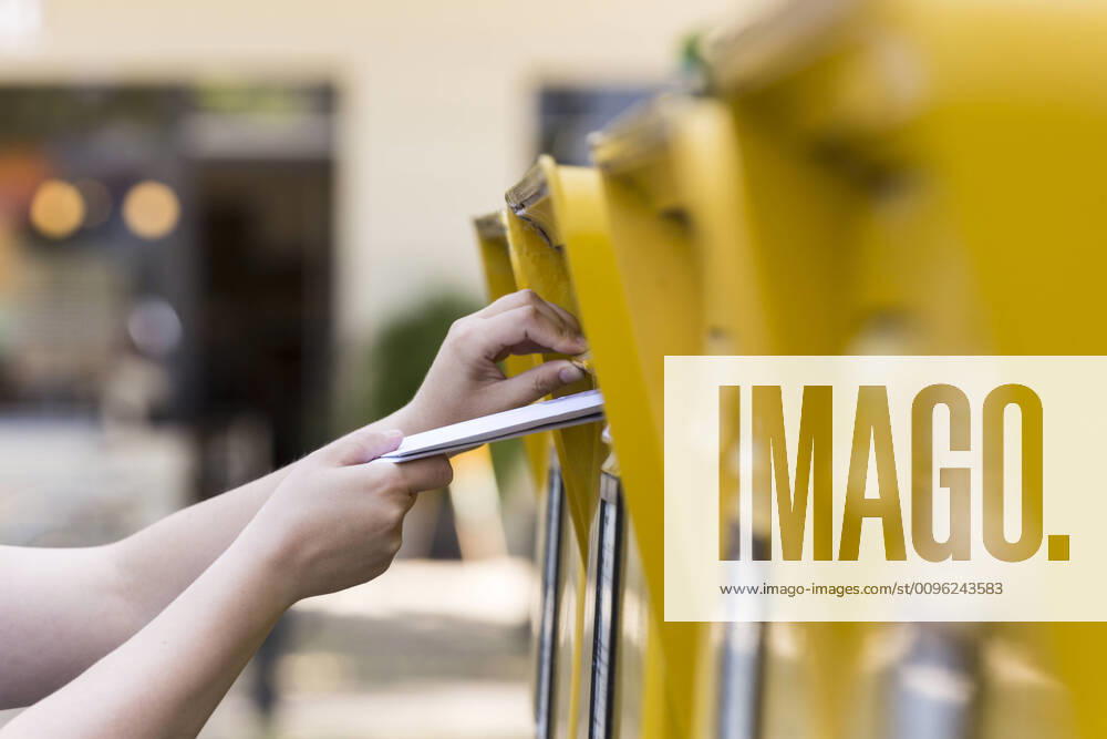 Woman puts letter in a Deutsche Post AG mailbox