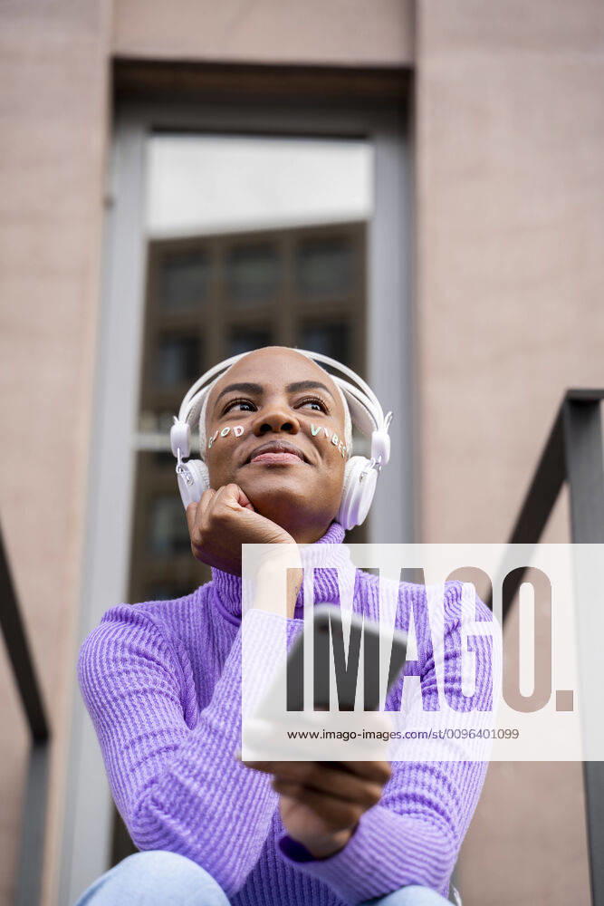 Portrait of white haired woman with white headphones and stickers in her face listening to music and laughing model released Symbolfoto AFVF05022