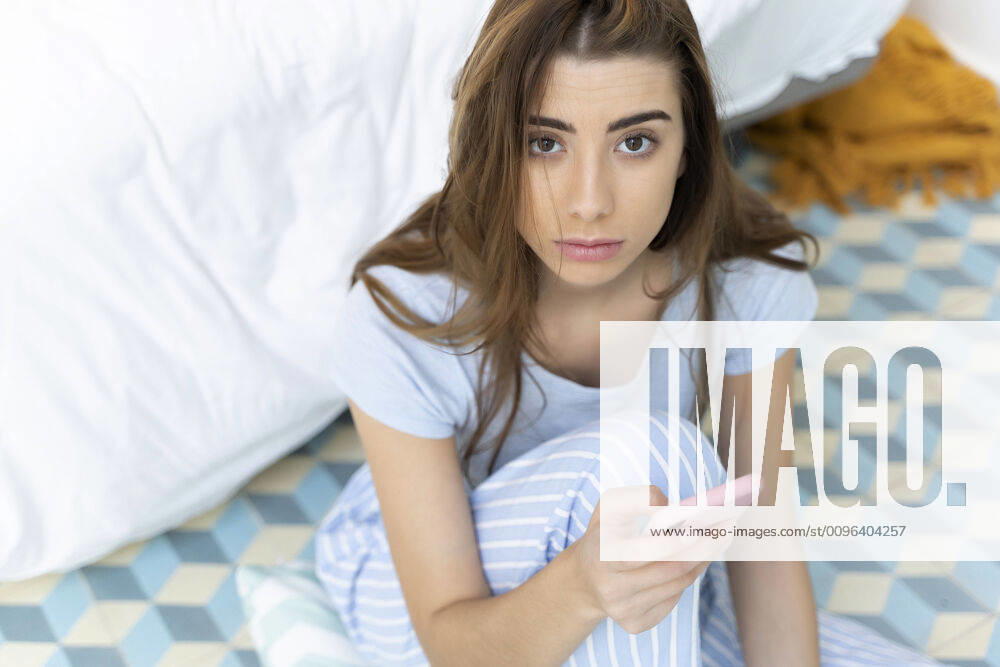 Portrait of young woman holding smartphone in bedroom model released Symbolfoto property released ERRF02544