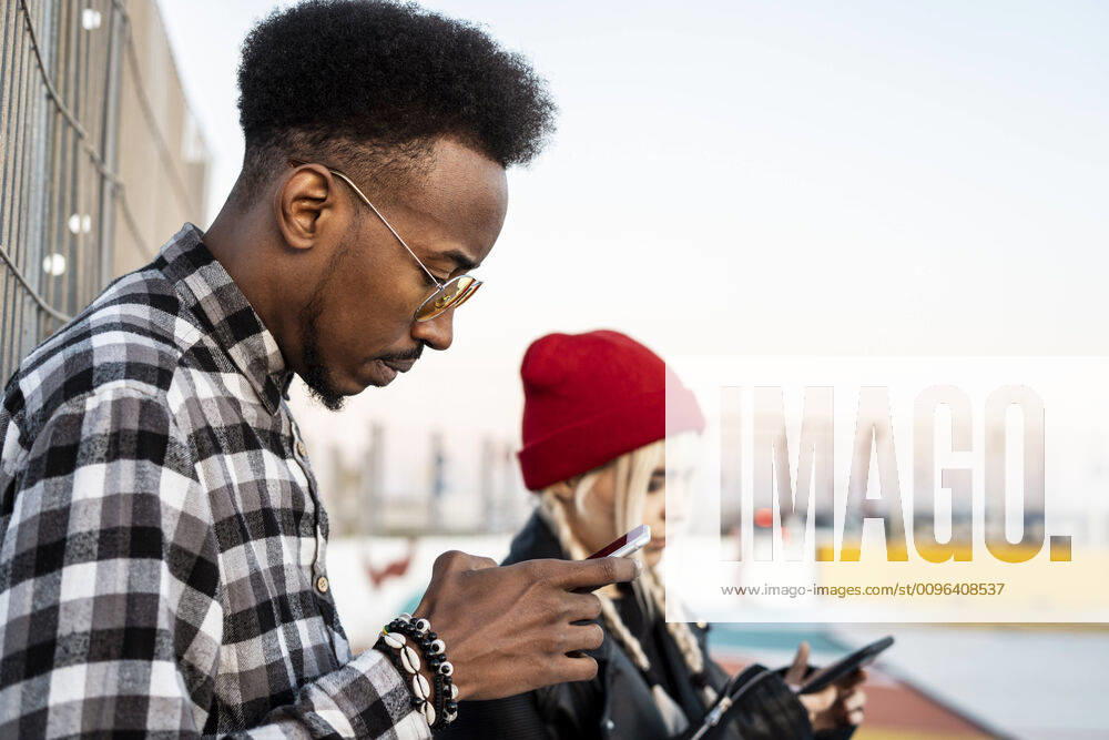 Young man using smartphone outdoors model released Symbolfoto RCPF00205