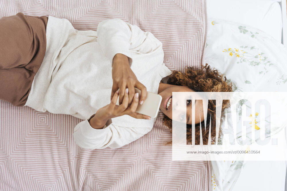 Young woman lying in bed using smartphone model released Symbolfoto property released VPIF01921
