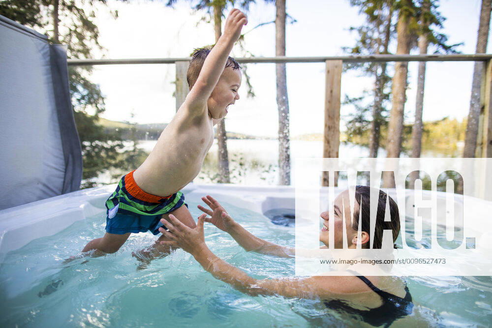Young boy jumping to mother in hot tub during vacation. Lac Le Jeune, BC, Canada CR_JDIP200102-245326-01
