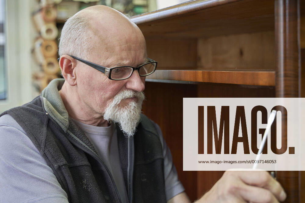 1 an antique carpenter attaches a hinge to a renovated baroque cabinet Russikon, Switzerland 1082501509