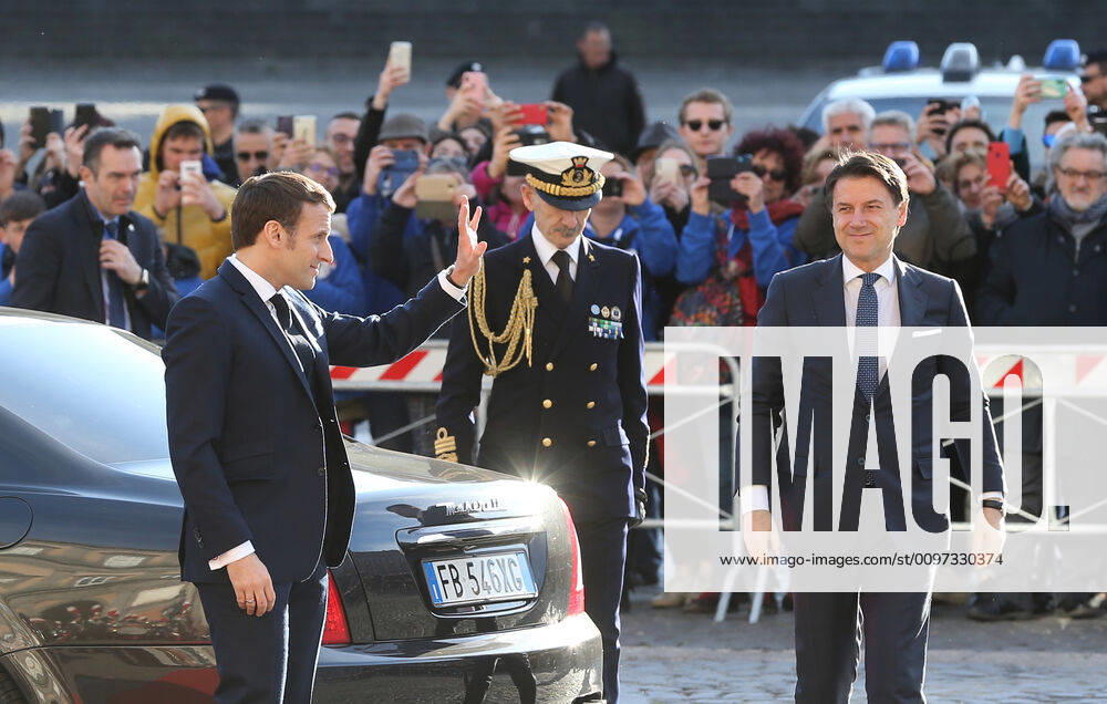 French President Emmanuel Macron waves to people (L) next to Italian Prime Minister Giuseppe Conte as arriving at the Royal Palace, venue of the XXXV Italian-French Summit