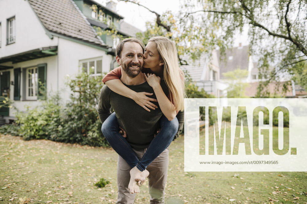 Woman kissing man, carrying her piggyback in garden model released Symbolfoto property released KNSF07220