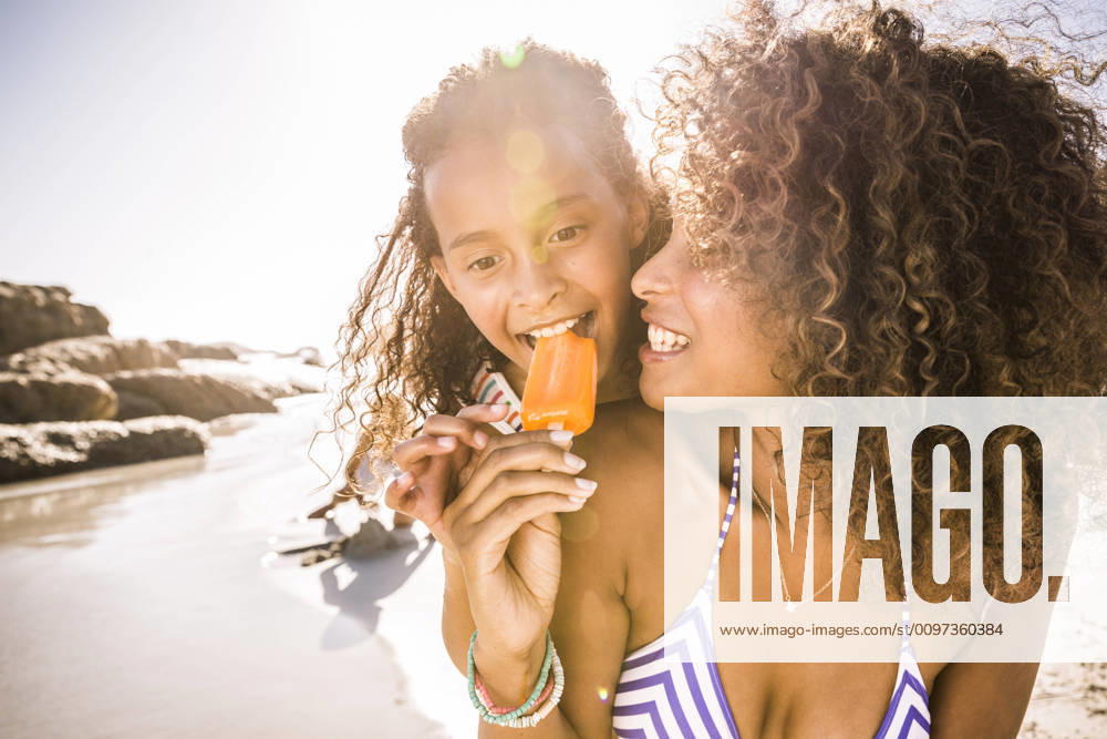 Woman sharing popsicle with daughter on the beach model released Symbolfoto SDAHF00467