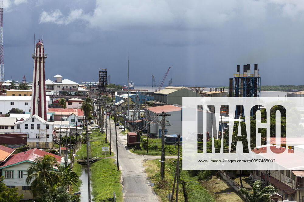 The Light House, Georgetown, Guyana was built of brick in 1830 to replace an earlier wooden one built by the Dutch. It is octagonal in shape and rises 103 feet. It is a Guyana National Monument. The Stabroek Market clock tower is visible to the left in the distance. The view is looking down Water Street toward the docks on the Demerara River. The stacks of the power generation plant are on the right in the foreground. Georgetown Demerara-Mahaica Region Guyana