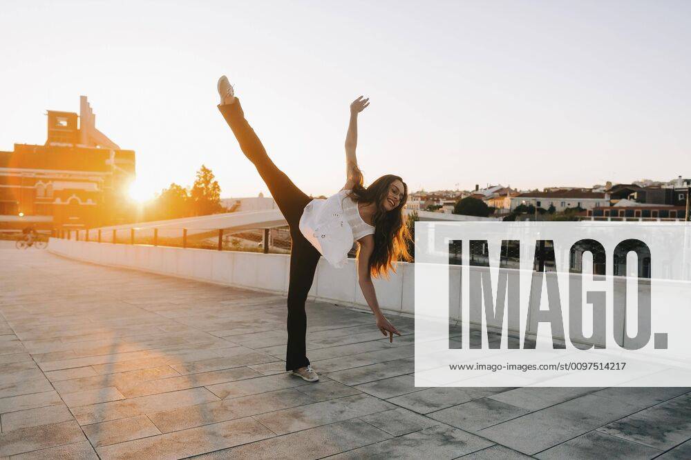 Playful young female dancer doing standing splits in sunny city park , Portugal Lisbon Belem