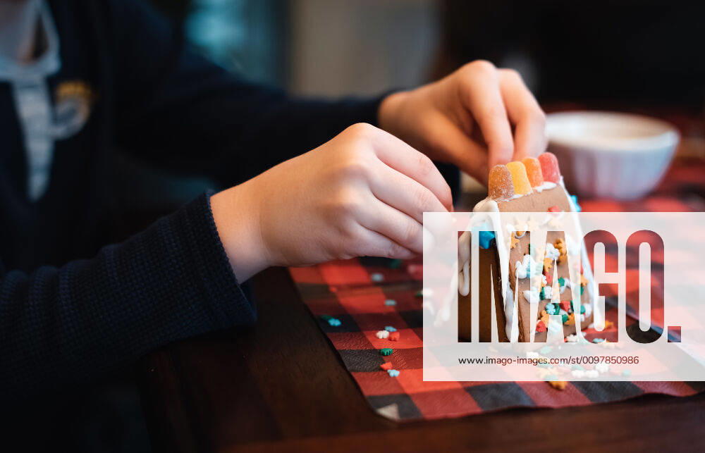 Close up of child s hands putting candies on a gingerbread house. Kingston, ON, Canada ,model released, Symbolfoto CR_DOHO200116C-281185-01